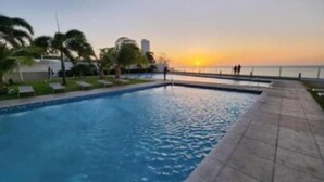 Una piscina con vista al atardecer sobre el océano.