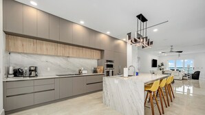 Une cuisine moderne dotée d’un plan de travail en marbre, d’appareils électroménagers intégrés et d’un coin bar avec des tabourets.