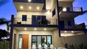 Une maison moderne à deux étages, dotée d’une piscine, d’un balcon et d’une porte donnant sur l’entrée.