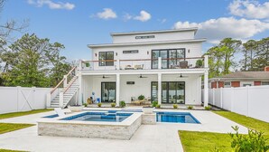 Une maison moderne à deux étages, dotée d’un grand jardin, d’une piscine et d’un patio couvert.