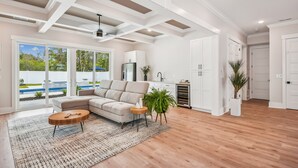 Un salon spacieux avec un grand canapé d’angle, une table basse ronde et une vue sur une piscine, visible à travers des portes vitrées.