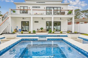 Una casa de dos pisos con piscina, un patio cubierto y una escalera que lleva al nivel superior.