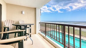 A balcony with a pool view, a table, and two chairs. - Sea Marsh I 104 - 3BD/2.5BA - Oceanfront (North Myrtle Beach)