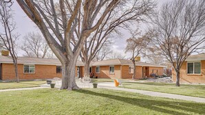 Un quartier résidentiel avec des maisons en briques, une pelouse verdoyante et un grand arbre au premier plan.
