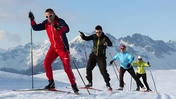 A group of people cross-country skiing on a snowy mountain with a clear sky.