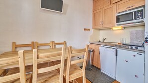 Une cuisine compacte dotée de meubles en bois, d’un four à micro-ondes, d’un lave-vaisselle et d’un petit réfrigérateur.