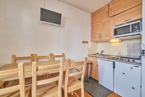 Una cocina compacta con armarios de madera, microondas, lavavajillas y un refrigerador pequeño.