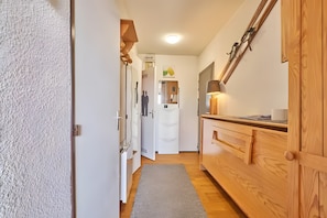 A narrow hallway with a wooden cabinet, a white door, and a small rug. - Apartment 'Le Val d'Huez' with Mountain View, Balcony and Shared Garage (huez)