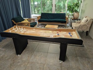 A foosball table in a room with a sofa, chairs, and large windows.