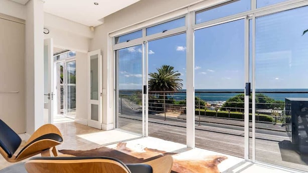 Una habitación moderna con grandes puertas correderas de vidrio que dan a un balcón con vistas al mar.