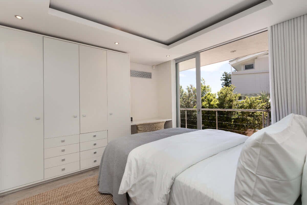 Une chambre dotée d’une grande armoire, d’un lit avec une literie blanche et offrant une vue sur l’extérieur grâce à une grande fenêtre.