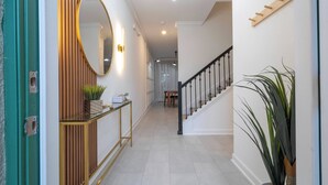 Un couloir avec une console en bois, un miroir et un escalier.