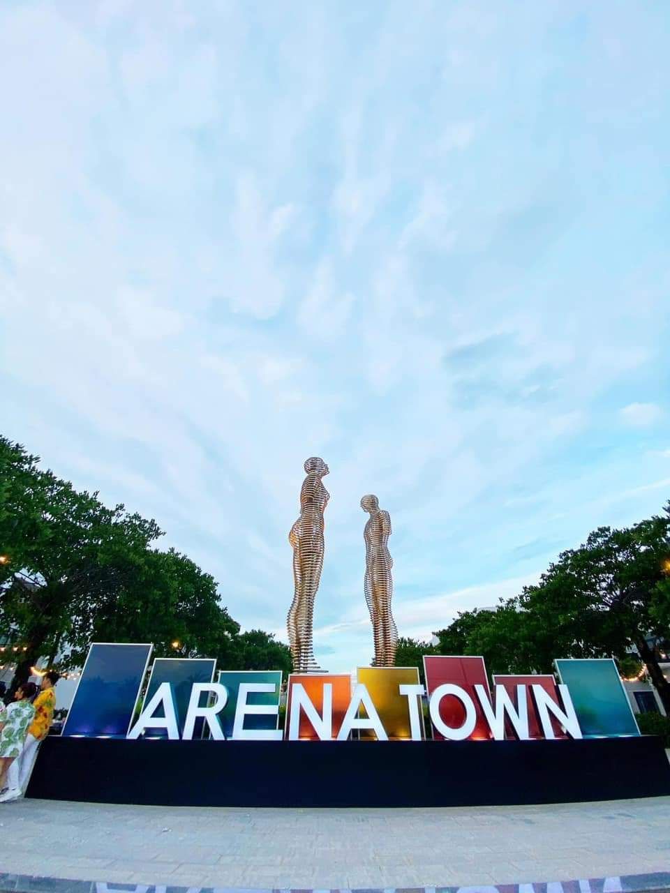 Un cartel con el texto 'ARENATOWN' y dos esculturas abstractas.