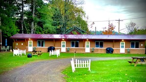 Un motel avec un toit rouge, de nombreuses fenêtres et une clôture blanche en bois devant.