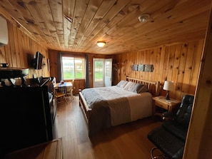 A wooden cabin interior with a bed, a desk, and a chair. - Ruth Lake Resort Cabin # 3 (Spurr Township)