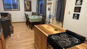 Une cuisine avec des meubles en bois, une cuisinière et un coin repas comprenant des chaises et une table.