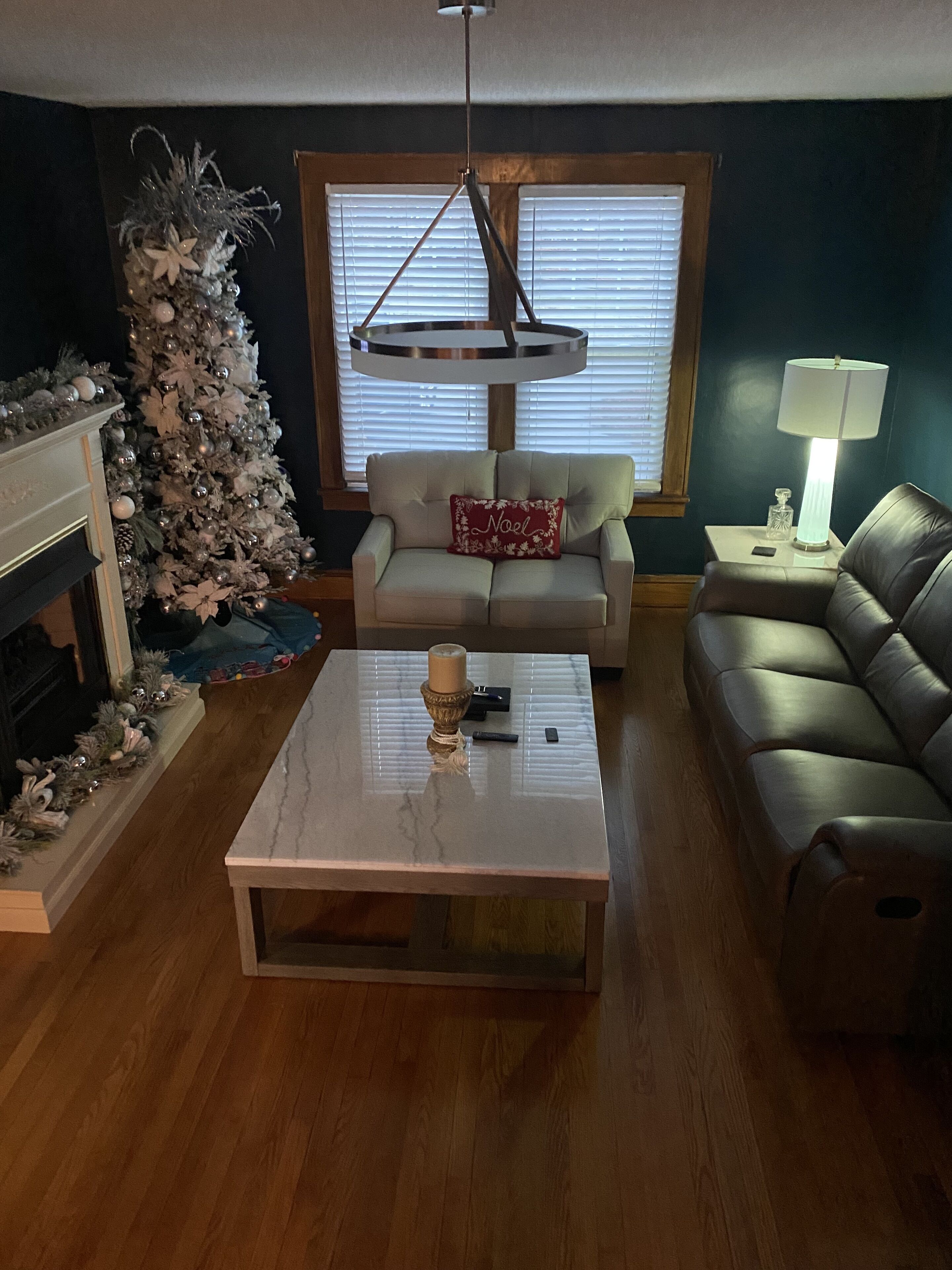 Un salon avec un sapin de Noël, un canapé, une table basse et une lampe.