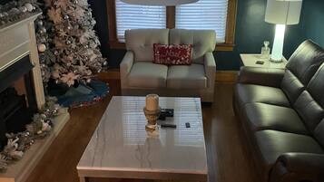 Un salon avec un sapin de Noël, un canapé, une table basse et une lampe.