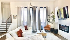 Ein modernes Wohnzimmer mit einem weißen Sofa, einem Couchtisch und einem an der Wand montierten Fernseher.