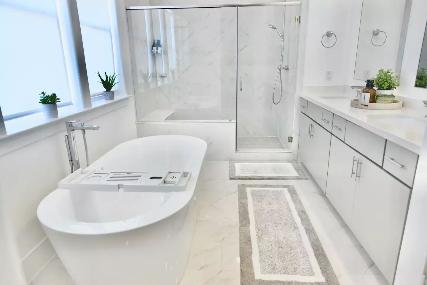 Ein modernes Badezimmer mit einer freistehenden Badewanne, einer begehbaren Dusche und einem Waschtisch mit Spiegel.