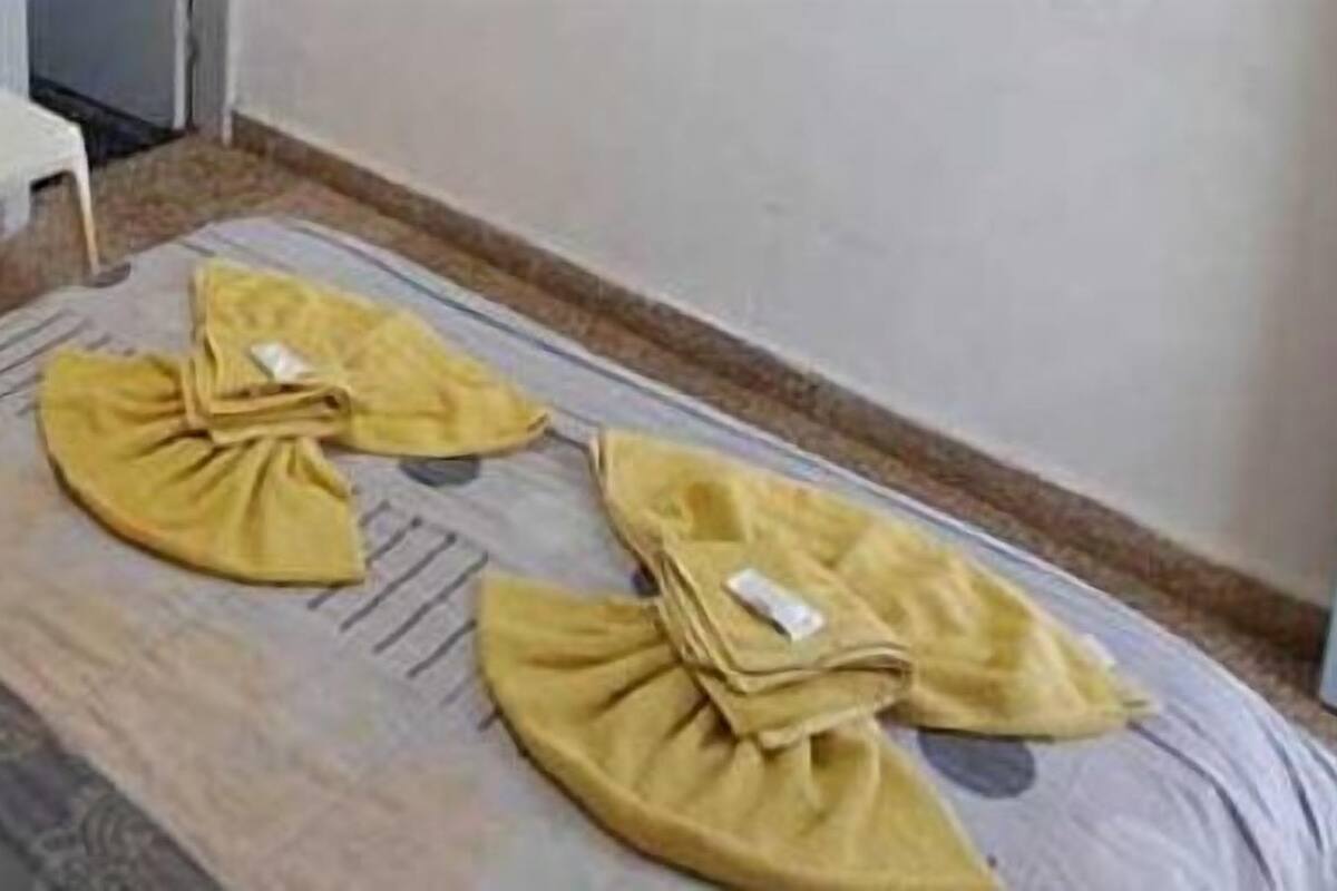 Una habitación pequeña con una cama, una silla, una mesita y un calentador en la pared.
