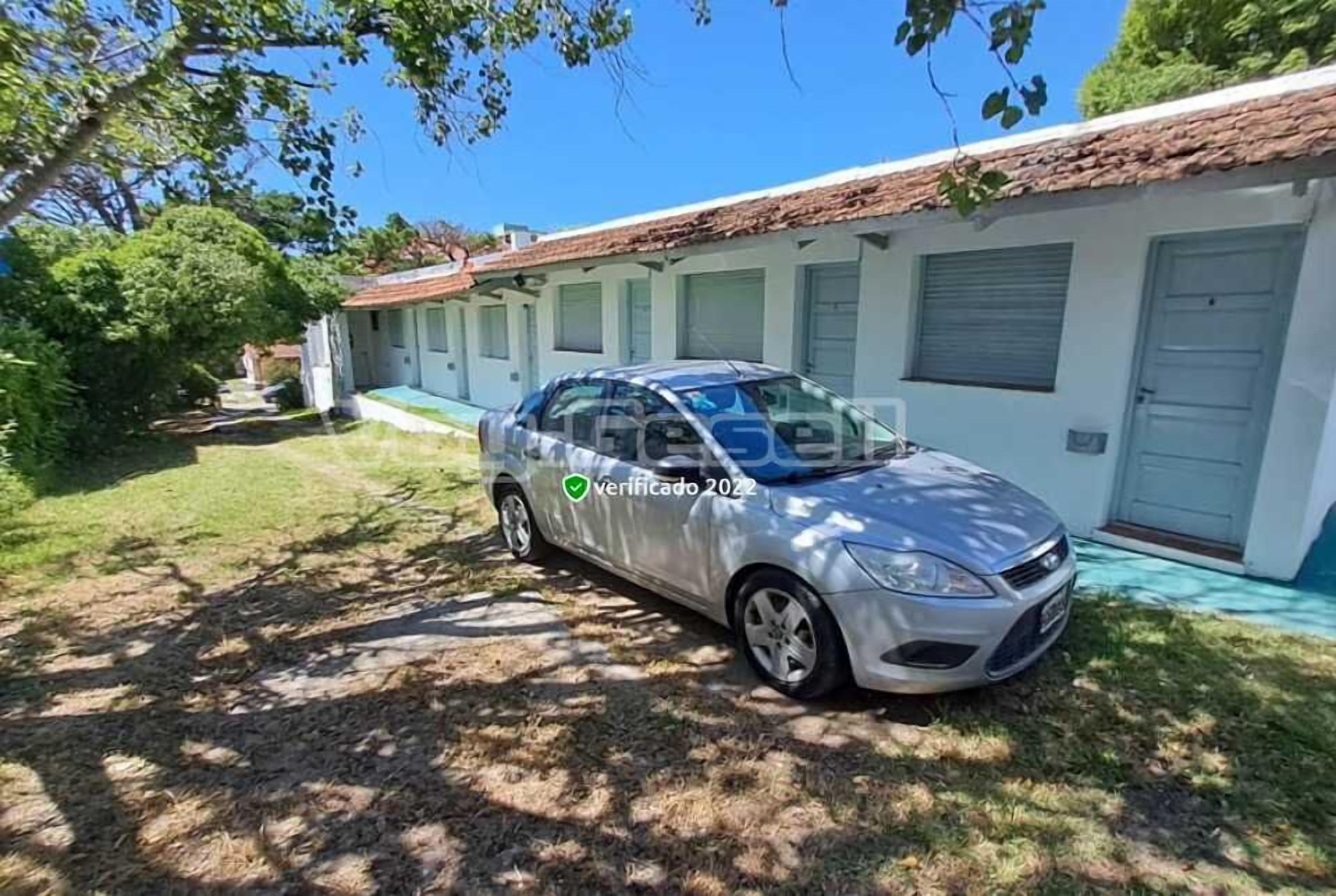 A silver car parked in front of a building with a tiled roof and a white exterior.