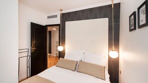 Un dormitorio con cama, mesitas de noche, armario y una puerta.