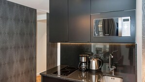 Una cocina moderna con microondas integrado, cafetera y lavamanos.