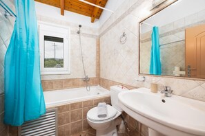 A bathroom with a bathtub, toilet, sink, and a window with a view.