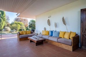 A covered patio area with a sofa set, a coffee table, and decorative wall art.