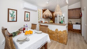 Un espace repas agrémenté d’un mur en pierre, une cuisine avec des meubles en bois et un luminaire suspendu.