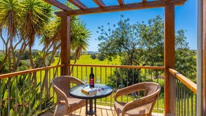 Une pergola en bois, agrémentée de deux fauteuils en osier et d’une petite table, offrant une vue sur un paysage verdoyant et luxuriant.