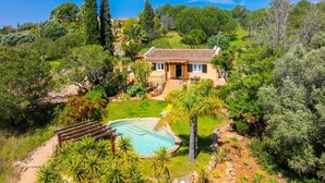 Une maison avec une piscine, entourée d’une végétation luxuriante et dotée d’un jardin bien entretenu.