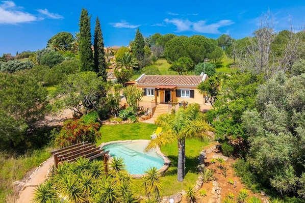 Ein Haus mit Swimmingpool, umgeben von üppiger Vegetation und einem gepflegten Garten.