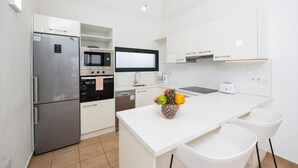 A modern kitchen with white cabinetry, a stainless steel refrigerator, an oven, a microwave, a dishwasher, and a fruit bowl on the island. - Villa Dacil - Three Bedroom Villa, Sleeps 6 (Playa Blanca)