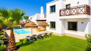 A modern two-story building with a swimming pool, outdoor seating, and a well-maintained lawn. - Villa Dacil - Three Bedroom Villa, Sleeps 6 (Playa Blanca)