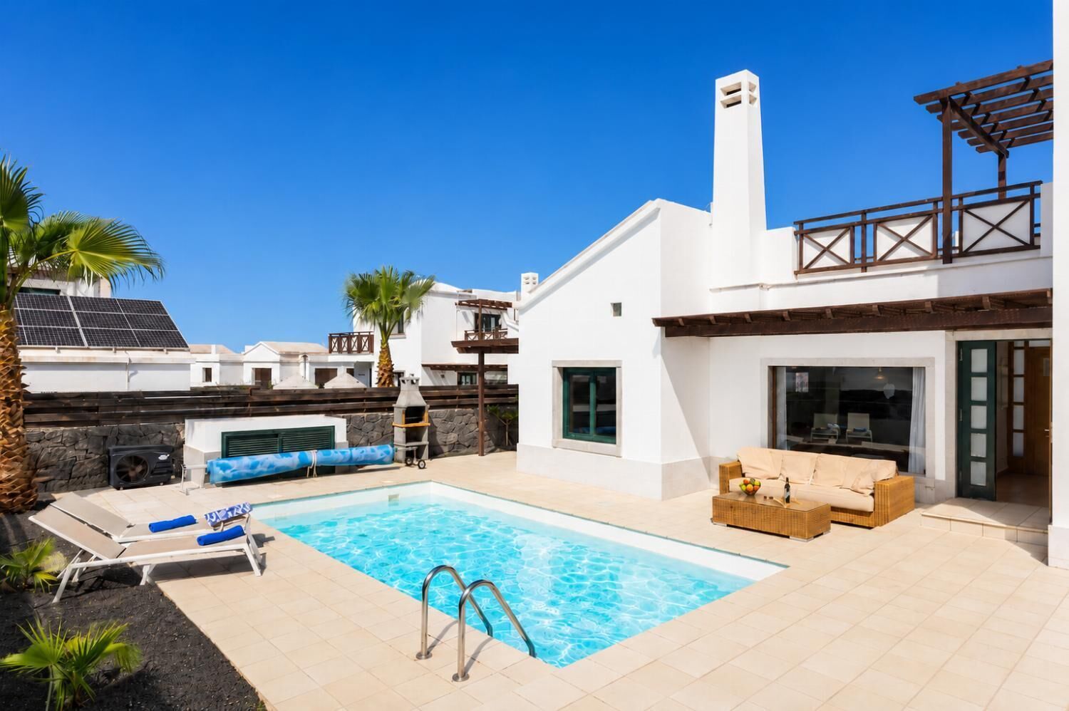 A modern outdoor pool area with a hot tub, lounge chairs, and a pergola.