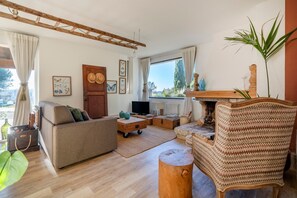 Ett vardagsrum med en soffa, ett soffbord i trä, en tv och en öppen spis.