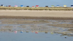 A beach with several colorful beach huts in the background.