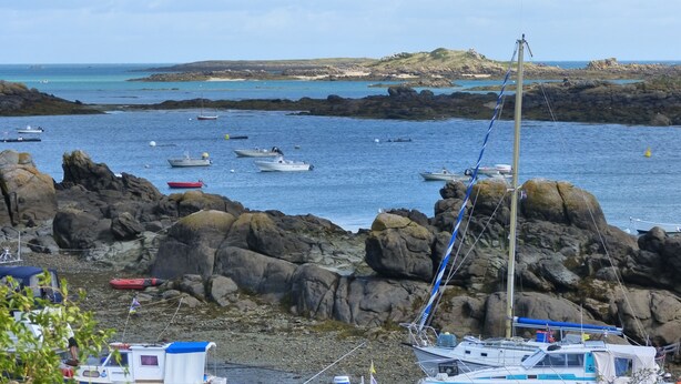 A rocky coastal area with boats anchored near the shore.