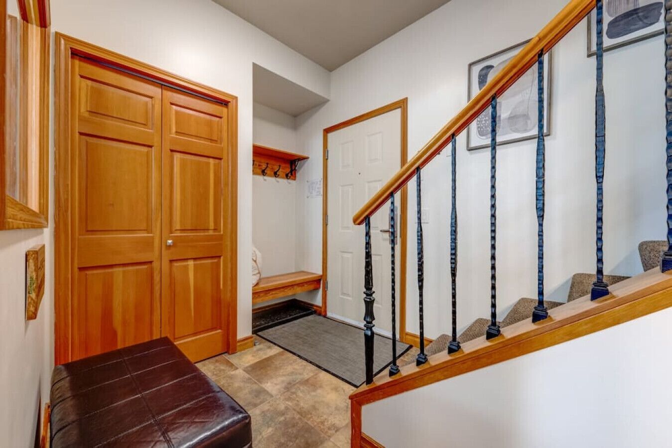 Un pasillo con un banco de madera, una puerta y una escalera con barandilla de madera.