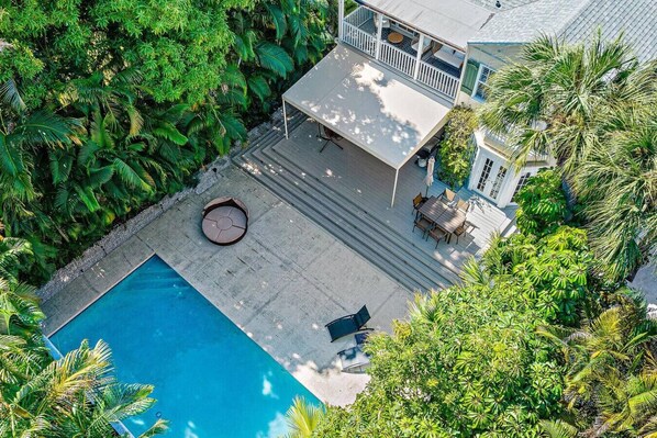Vue aérienne d’une maison avec une piscine, entourée d’une végétation luxuriante.