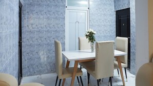 A dining area with a marble wall, a white door, and a ceiling fan. - Luxurious Apartment Complex Kumasi (Kumasi)