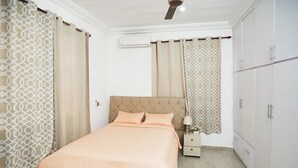 A bedroom with a bed, curtains, a nightstand, and a wardrobe. - Luxurious Apartment Complex Kumasi (Kumasi)