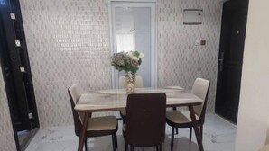 A dining area with a marble table and chairs, a vase with flowers, and a tiled floor. - Luxury complex at Agric Kumasi (Kumasi)
