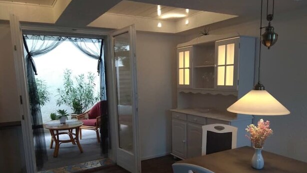 A room with a dining table, chairs, a lamp, and a view of the outdoors through a door. - Vacation apartment near Baden-Baden (Bühl)