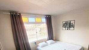 A hotel room with two single beds, a window with curtains, a wall-mounted artwork, and a view of the outside. - Jf Studio Hotel (São Luís)