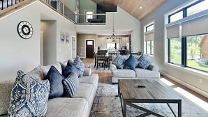 A spacious living room with a high ceiling, a staircase, and a dining area. - Heavenly Summit by Taylor Made Deep Creek (McHenry)