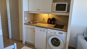 A compact kitchen with a dishwasher, washing machine, and a microwave. - Superbe Vue Mer 2 Pièces Climatisé Les Restanques (Grimaud)