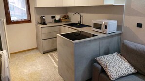 A compact kitchenette with a built-in microwave, a coffee maker, and a sink.